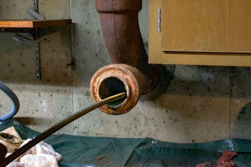 Plumber running a camera and cleaning machine through a drain line