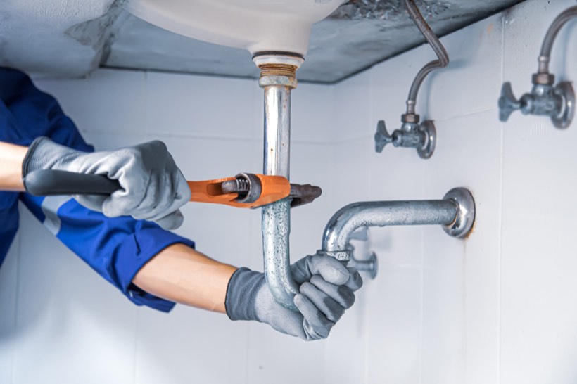 Plumber repairing a pipe under a sink
